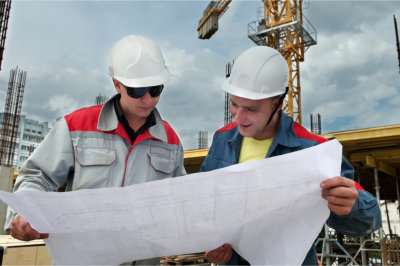 Two engineer builders examining blueprint at construction site